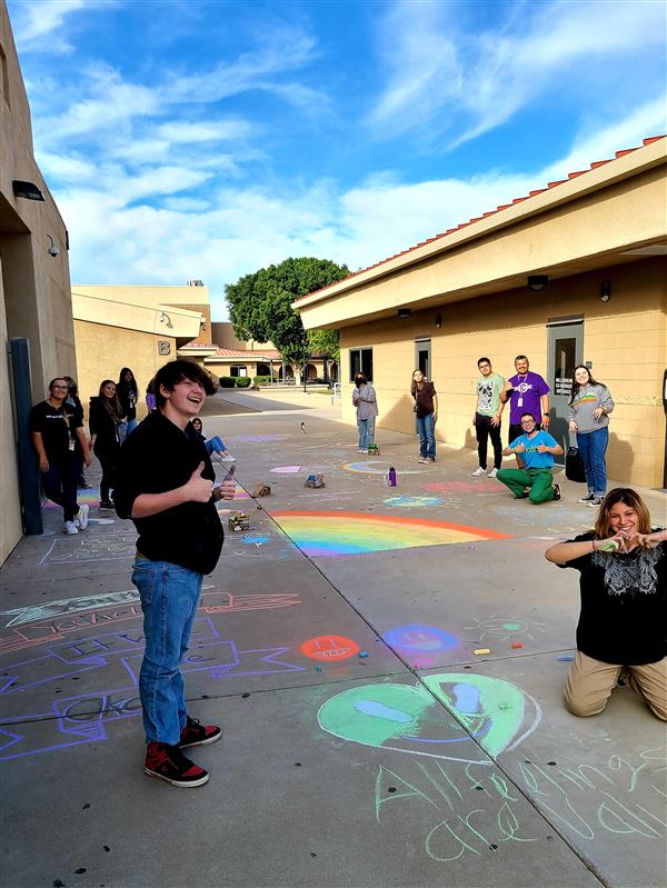 Students writing positive messages on the sidewalk to encourage staff and students.